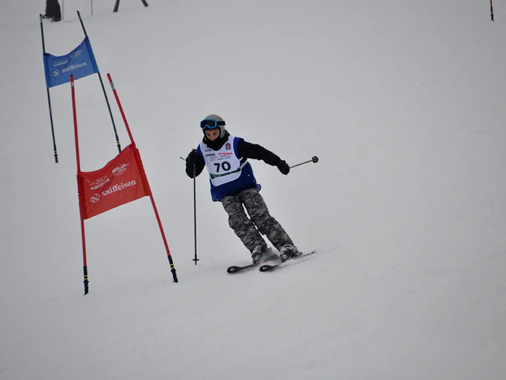 Skifahrer mit Startnummer 70 umfährt ein rotes Tor.